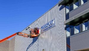 Installatie van verlichte doosletters op een bedrijfspand met hoogwerker.